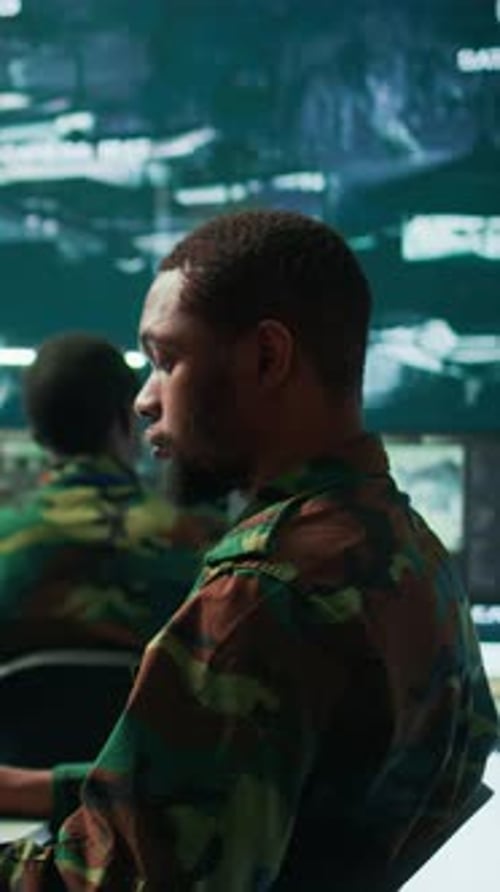 Man in Camouflage Using Computer in Dark Room