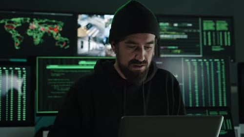 Man Hacking on Laptop in Dark Room