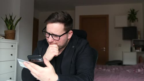 Man Using Phone and Credit Card Indoors