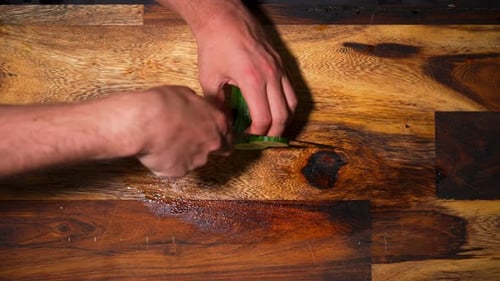 Top view of a male hand chopping a fresh cucumber on cutting board in slowmotion
