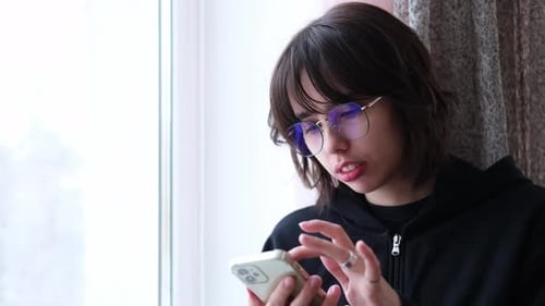 Teen Smiling While Using Cell Phone Indoors