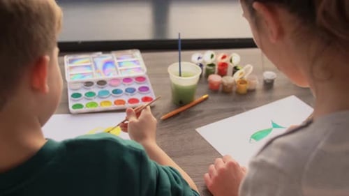 Children Painting Together at Table Indoors