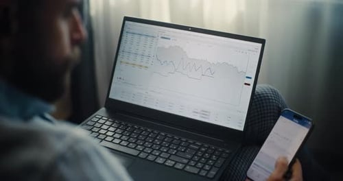 Close Up of Financial Expert Working on Smartphone and Laptop in Online Trading App