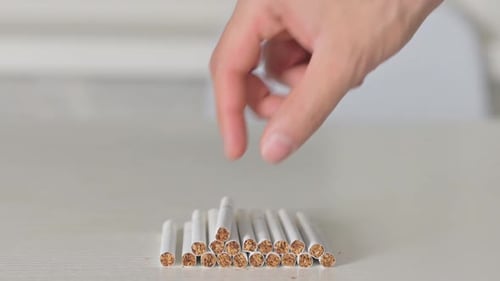 Close up of Hand Picking Up a Cigarette