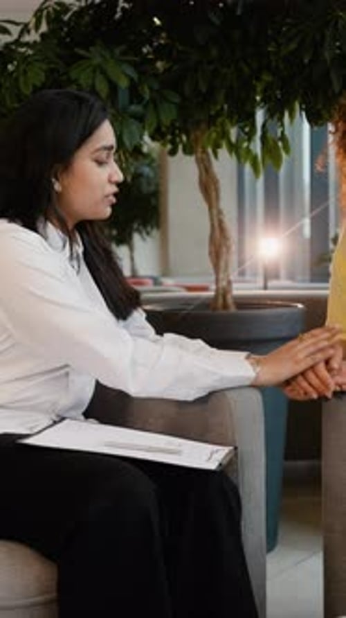 Women Talking and Holding Hands in Lobby