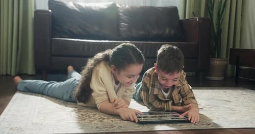 Children Lying on Rug Using Tablet at Home