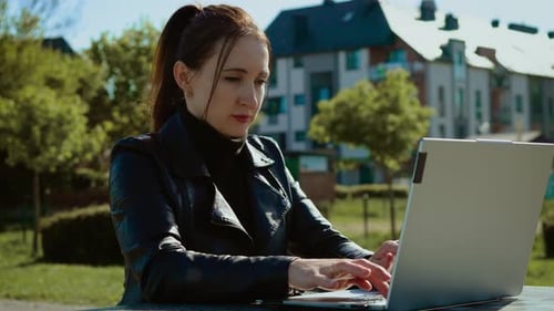 Woman Working on Laptop in City Park Female Freelancer Typing Outdoors on Sunny Day Remote