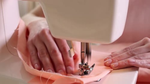 Woman sewing fabric with professional machine in workshop, closeup
