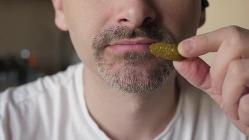 Adult Man Eats Pickled Gherkin Close-up