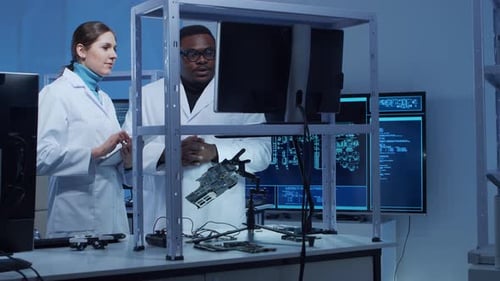 Vielfältiges Team von Mikroelektronikingenieuren diskutiert aktuelle Entwicklungen an einem wissenschaftlichen Laborarbeitsplatz von