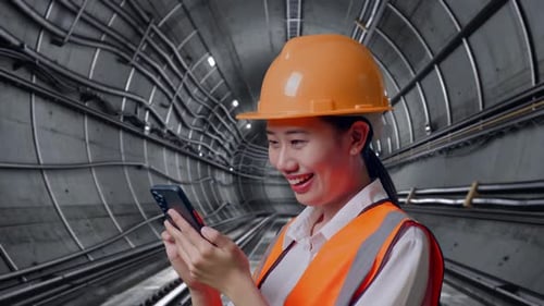 Close Up Side View Of Asian Female Engineer Using Smartphone In Subway Tunnel
