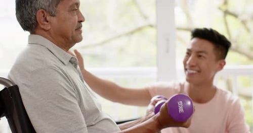 Senior Man Exercising with Assistance from Young Adult