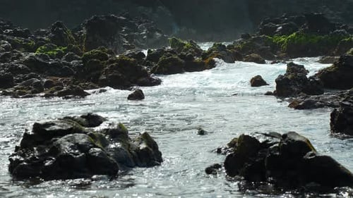 Water overflowing on rocks rushing towards the sea, static closeup slow motion