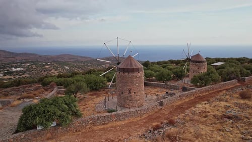 Ancient windmills overlooking the ocean on a Greek island at dusk