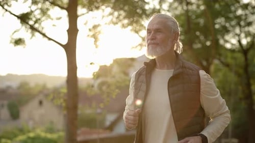 Active Senior Man Jogging Through Park at Sunrise