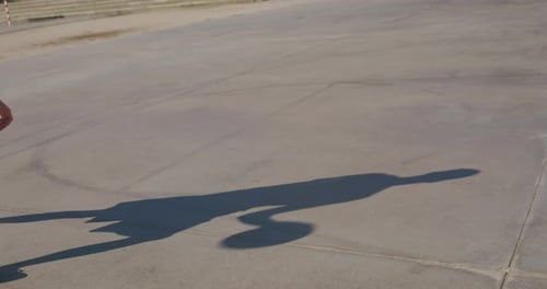 Medium shot of a silhouette of a young man playing alone on a basketball court in a street court in