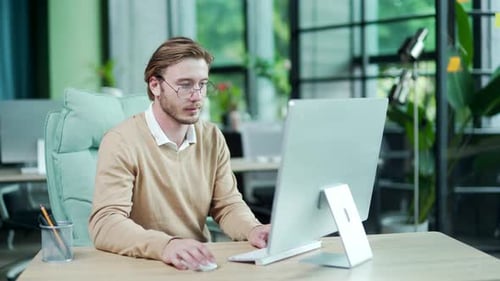 Porträt eines lächelnden bärtigen Geschäftsmannes, der am Surfen am Computer arbeitet und vieles mehr