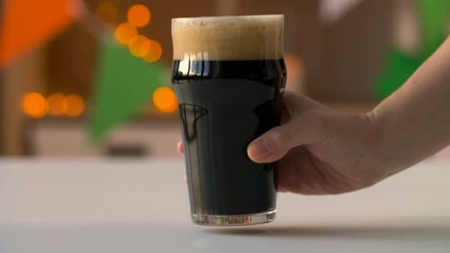 Holidays, Celebration And St Patrick'S Day Concept - Female Hand Putting Glass Of Dark Draught Be...