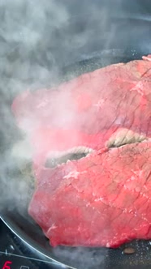 Raw Steaks Sizzling in Pan Close Up