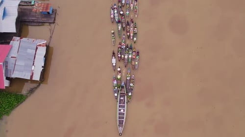 Motorboat pulling along traditional floating market boats on river Martapura