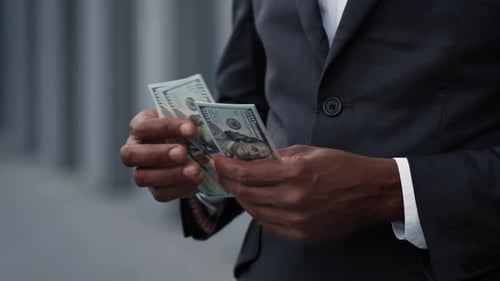 Close Up of Unrecognizable African American Businessman in Suit Counting Dollar Banknotes Standing