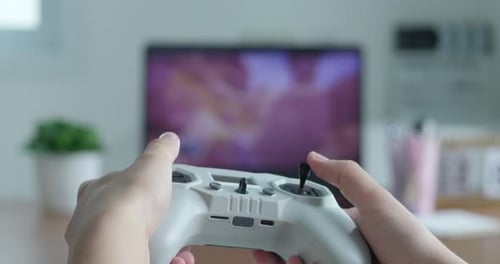 Rückansicht eines Teenagers, der ein Video-Joystick-Spiel mit Fernseher im Hintergrund in der Hand hält