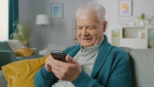 Senior man using smartphone on couch at home