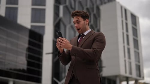 Excited Businessman Celebrates Good News on Phone Outdoors