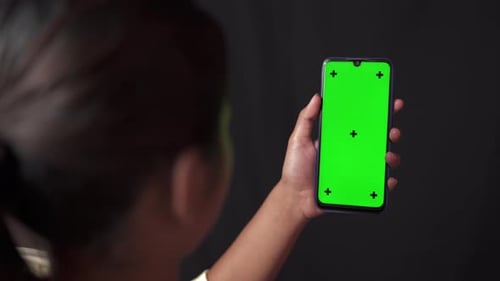 Green Screen Chroma key smartphone in girl hands in Black background room.