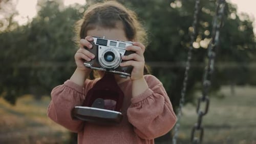 A Cute Little Girl Takes Her First Pictures of Nature with a Retro Camera Making First Steps in