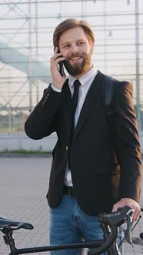 Man in Suit on Phone with Bicycle Outdoors