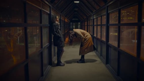 Two Adults Talking on an Enclosed Walkway at Night