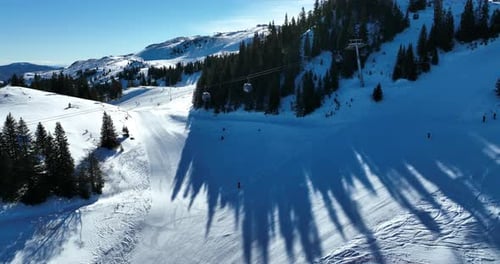 A ski resort in a mountain range dotted with pine forests on a clear sunny day