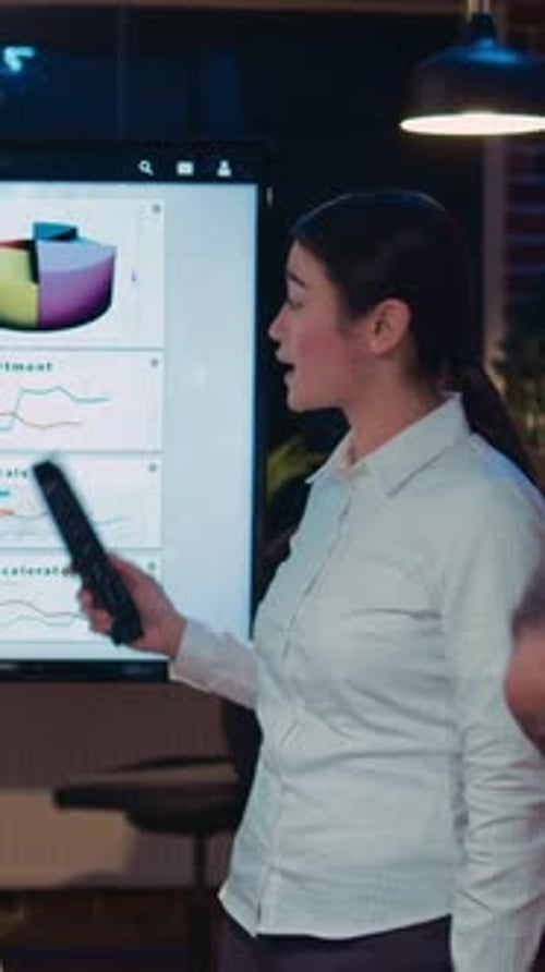 Young Woman Presents Data to Colleagues at Night