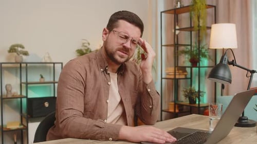 Bearded Man Working on Laptop with Headache