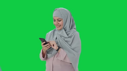 Happy Muslim businesswoman using phone Green screen
