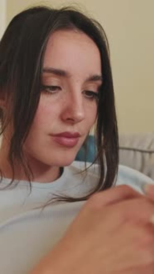 Close-up of young woman using phone while sitting on sofa at home