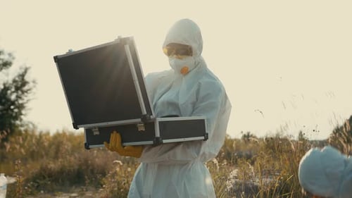 Scientists in Hazmat Suits Exchange Vials in Field