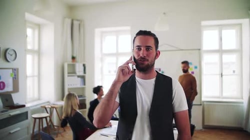 Young hipster businessman working with smartphone in modern office space