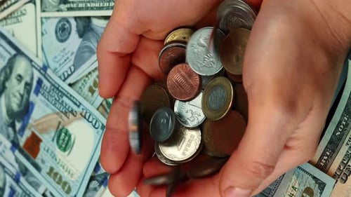 Coins falling into woman's hands against money background
