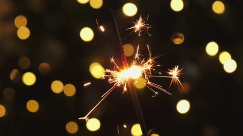 Festive Sparkler Burning with Twinkling Lights Background