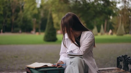 Students are Preparing for the Exam A Girl Sits on a Bench in the Institute Park and Prepares for