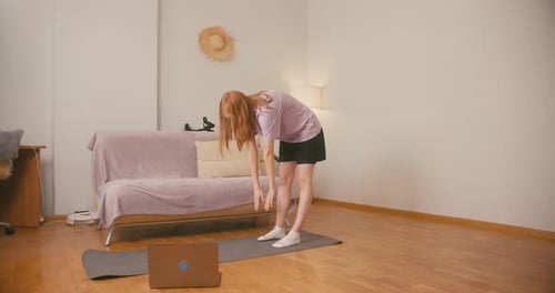 Redhaired Woman Tries to Place Hands on Floor During Training