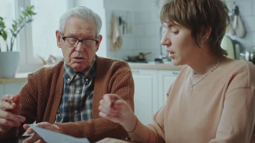 Financial Advisor Discussing Documents with Elderly Man at Home
