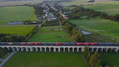 Aerial view of a train viaduct with a passing train and the surrounding countryside in the backgroun