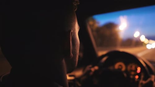 Young Man Holds Hands on Steering Wheel and Rides in Auto on Highway at Night Time Male Driver Moves