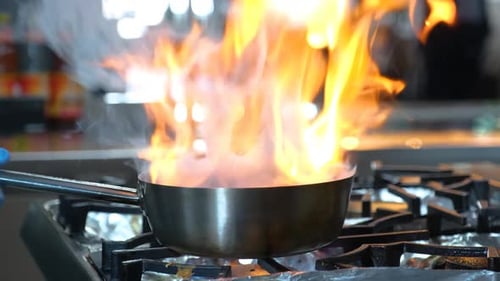 Close-up of a Restaurant Chef Cooking Food on Fire in the Restaurant Kitchen