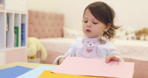 Cute Child Cutting Construction Paper with Scissors