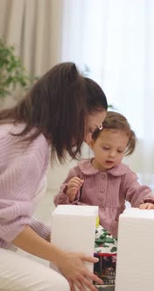 Mother and Child Opening Christmas Present at Home