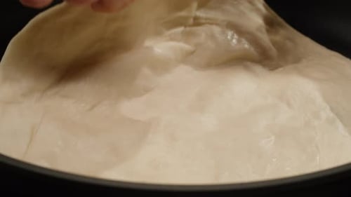 Indian Food Cooking Closeup View of a Woman's Hand Flipping a Naan Roti or Bread on Hot Metal Pan